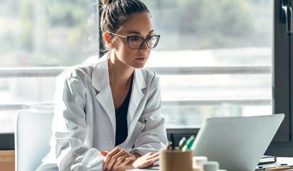 Doctor managing practice through a practice management in a laptop